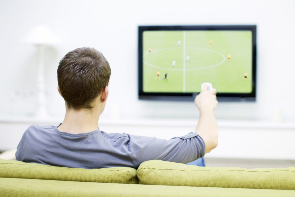 Ein Mann sitzt vor dem TV und schaut Fußball