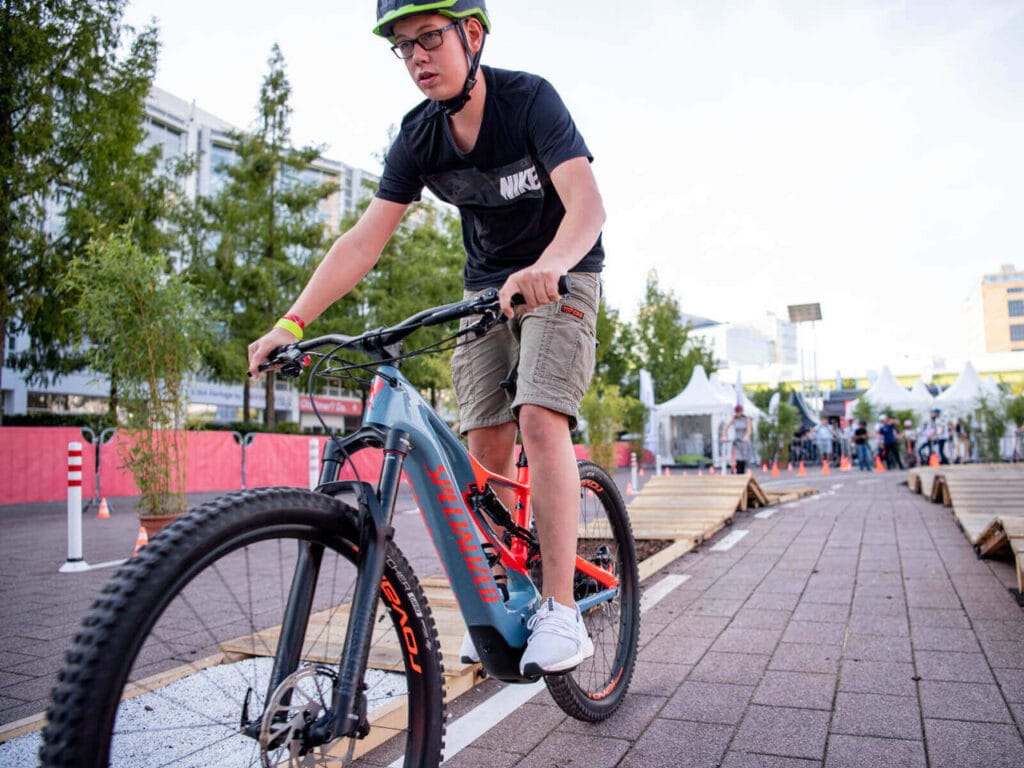 Jugendlicher auf E-Mountain Bike fährt Parcours