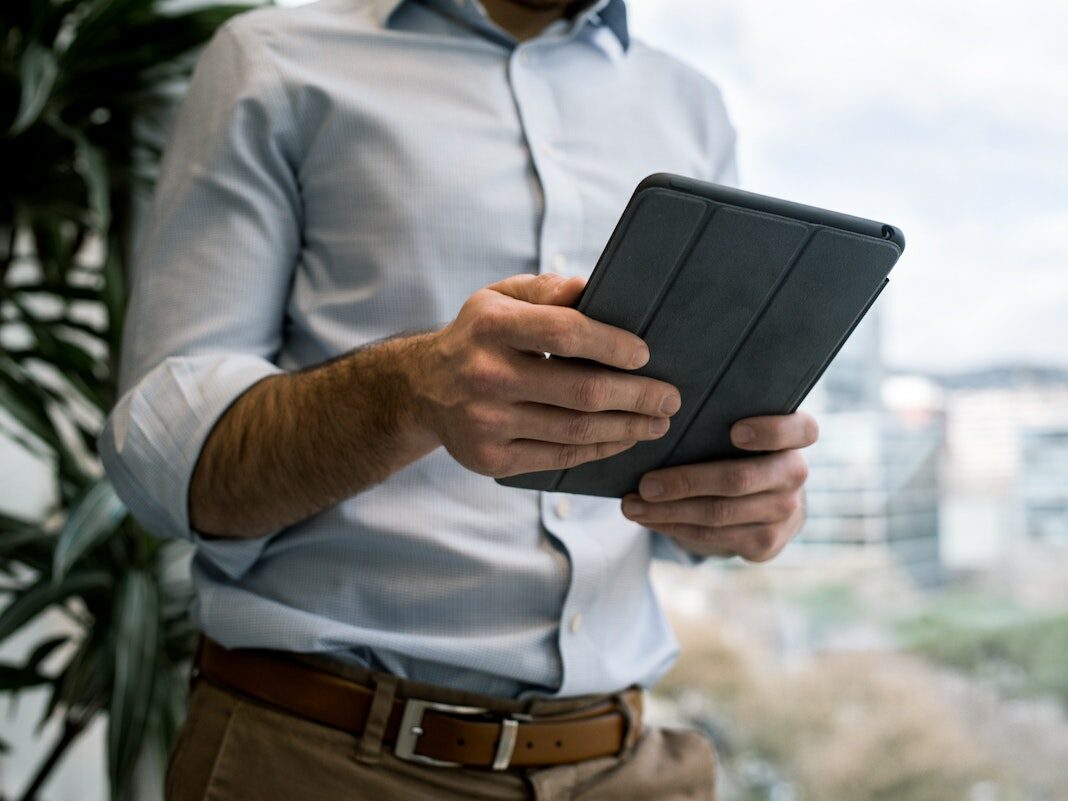 Ein Mann hÃ¤lt ein Tablet in der Hand.