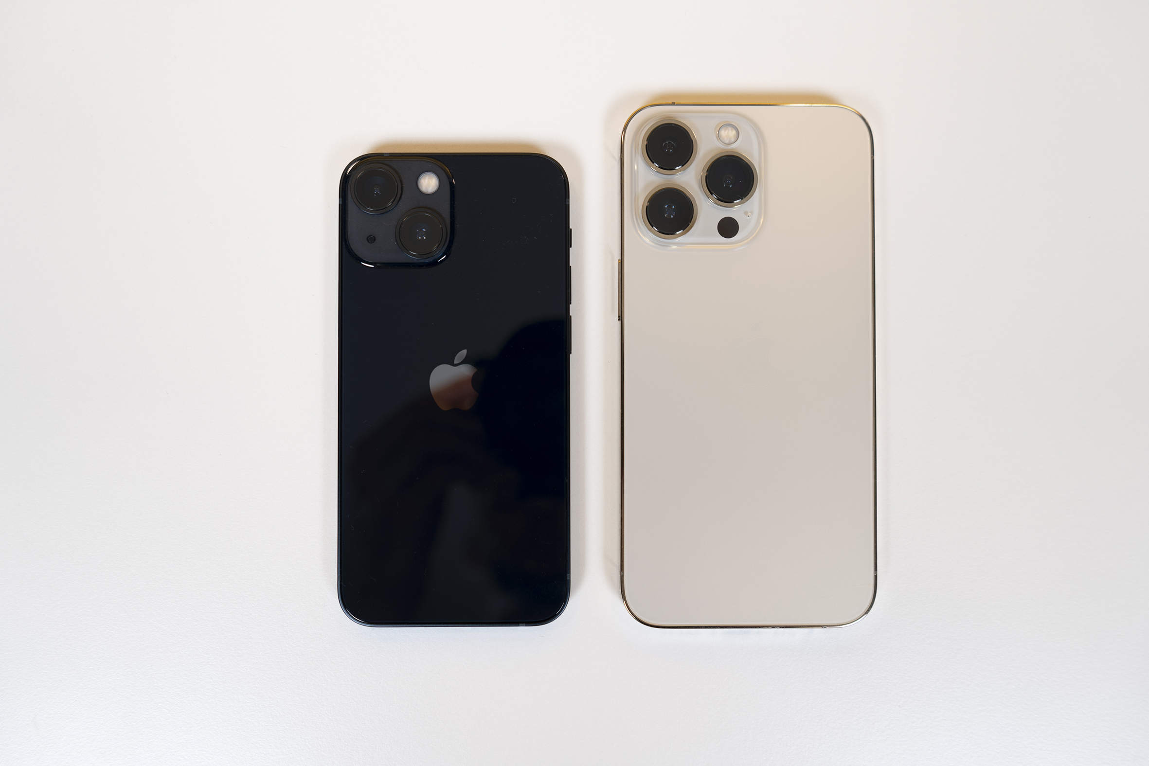 Schwarzes kleineres iPhone neben größerem hellem modell auf weißem Hintergrund