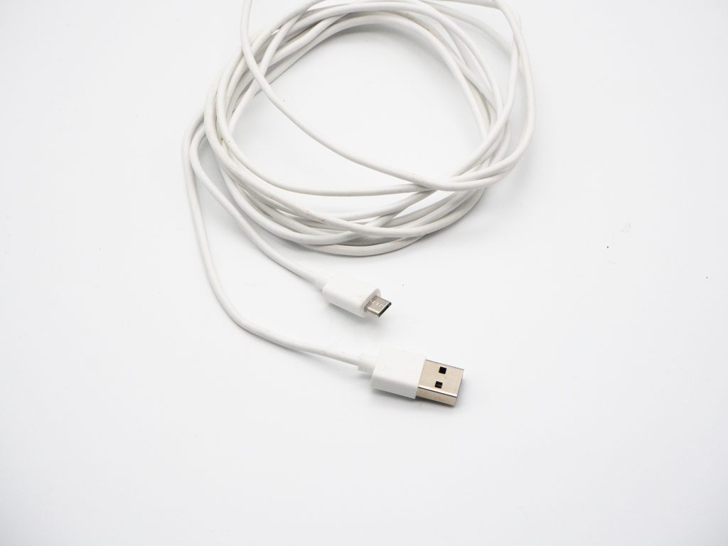 Weißes langes Kabel mit USB zusammengerollt auf weißem Grund