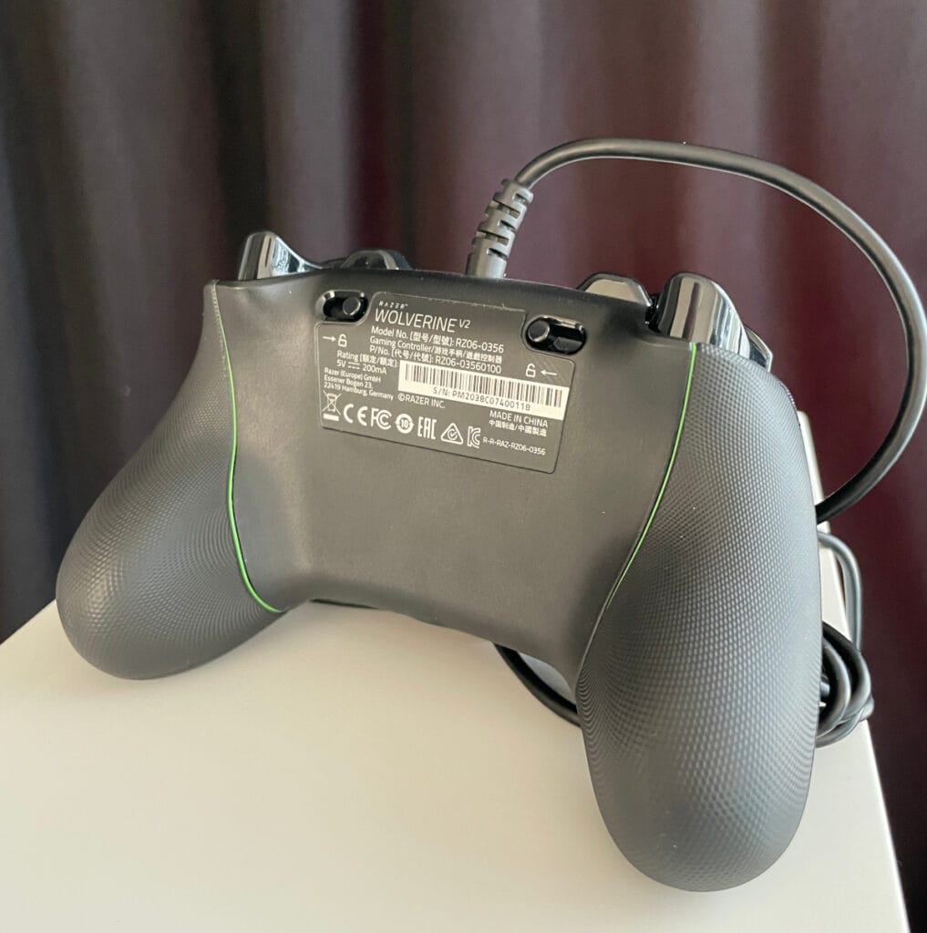 dunkler Controller von hinten steht auf weißem Podest vor schwarzem Vorhang