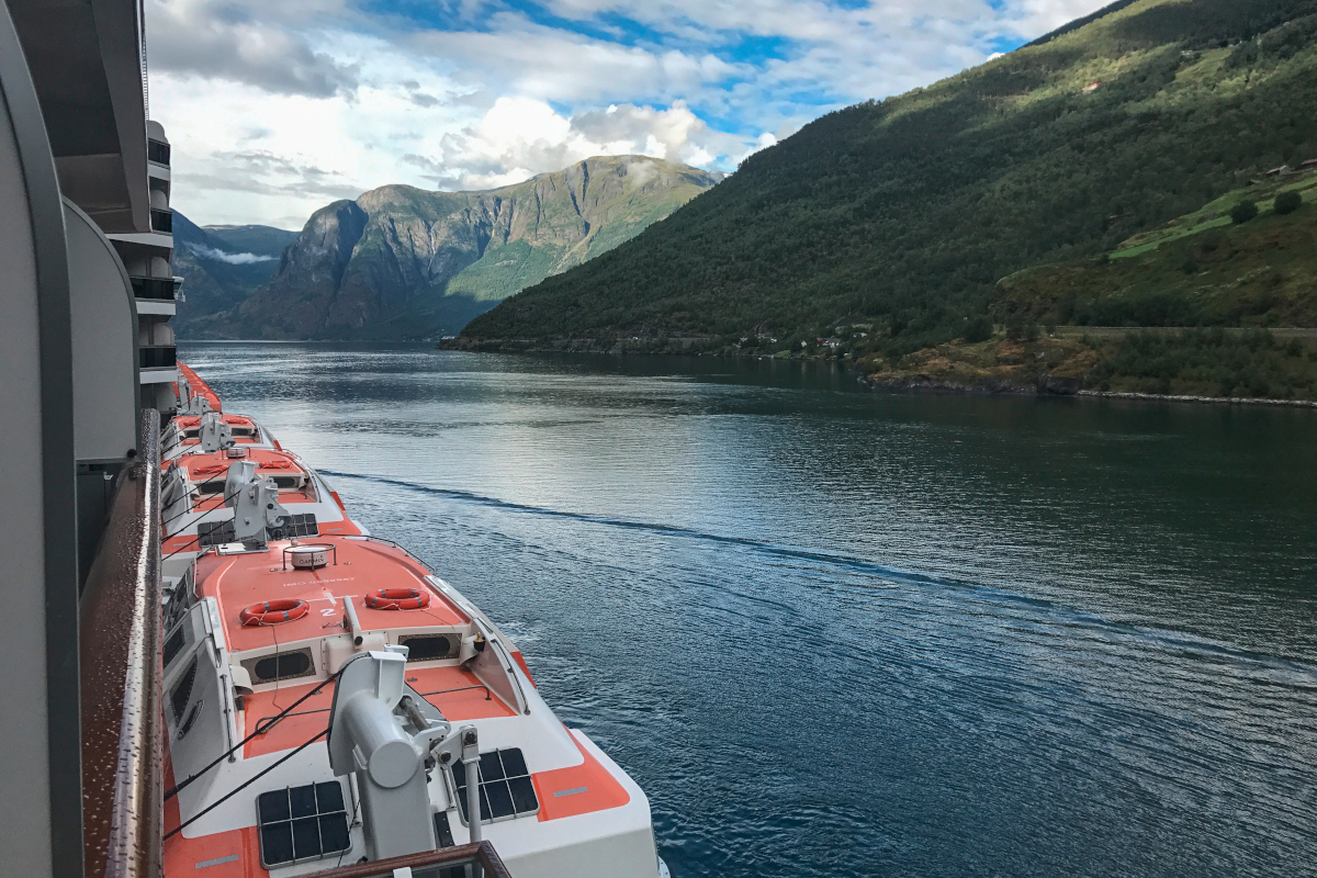 Blick von Schiff entlang Schiffseite und auf Wasser mit Bergen im Hintergrund