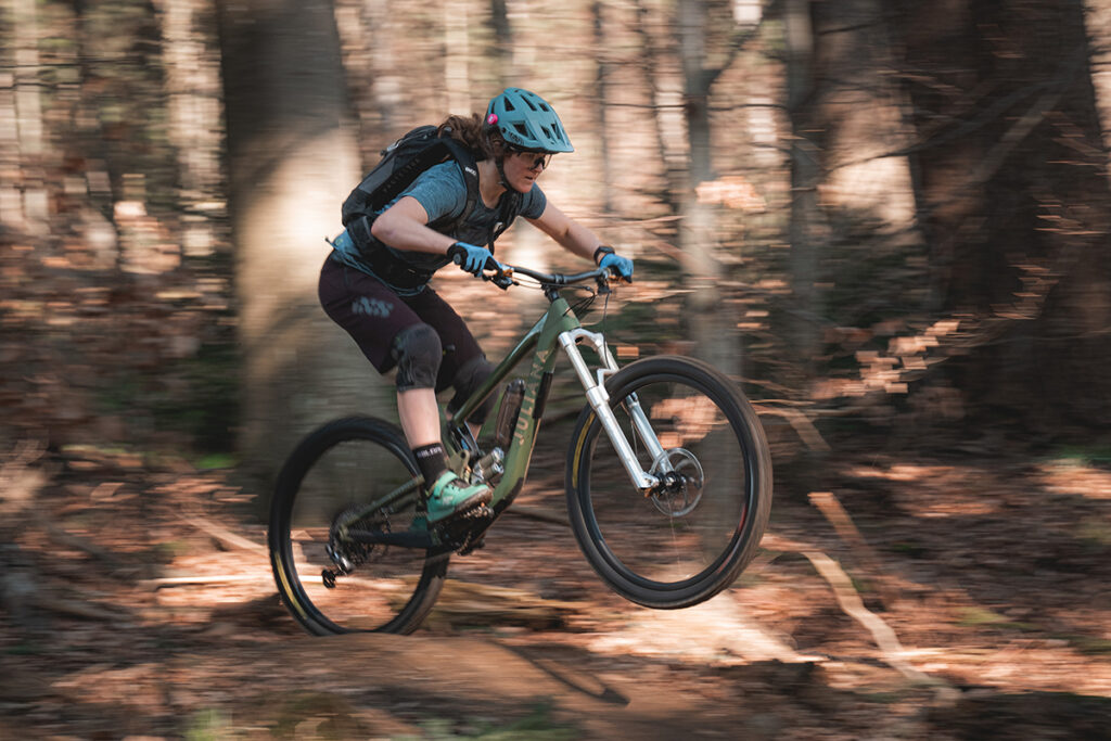 E-Bikerin beim Downhill-Fahren im Wald. Sie hat den smarten Schutzhelmsensor von Toscen an ihrem Helm besfestigt. 