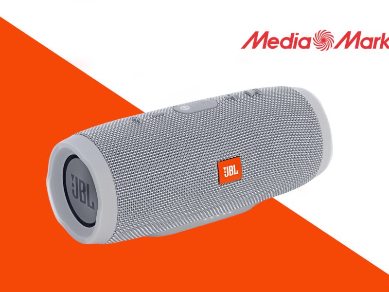 Grauer JBL Charge 3 Lautsprecher schräg von vorne vor orange weißem Hintergrund mit Media Markt Logo rechts oben in der Ecke