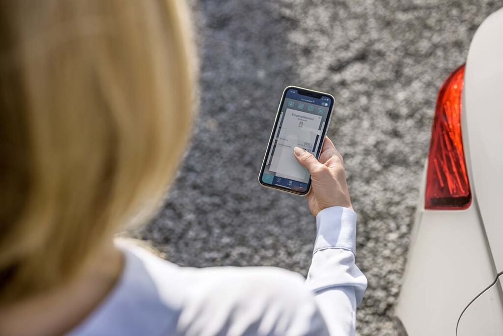 Eine Frau hält ein Smartphone in der Hand und konfiguriert Ihre Zutrittsregeln.