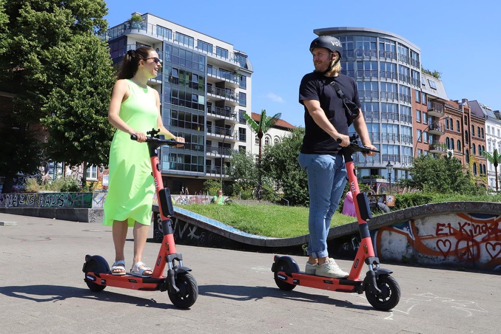 Zwei Menschen draußen auf E-Scooter fahrend.