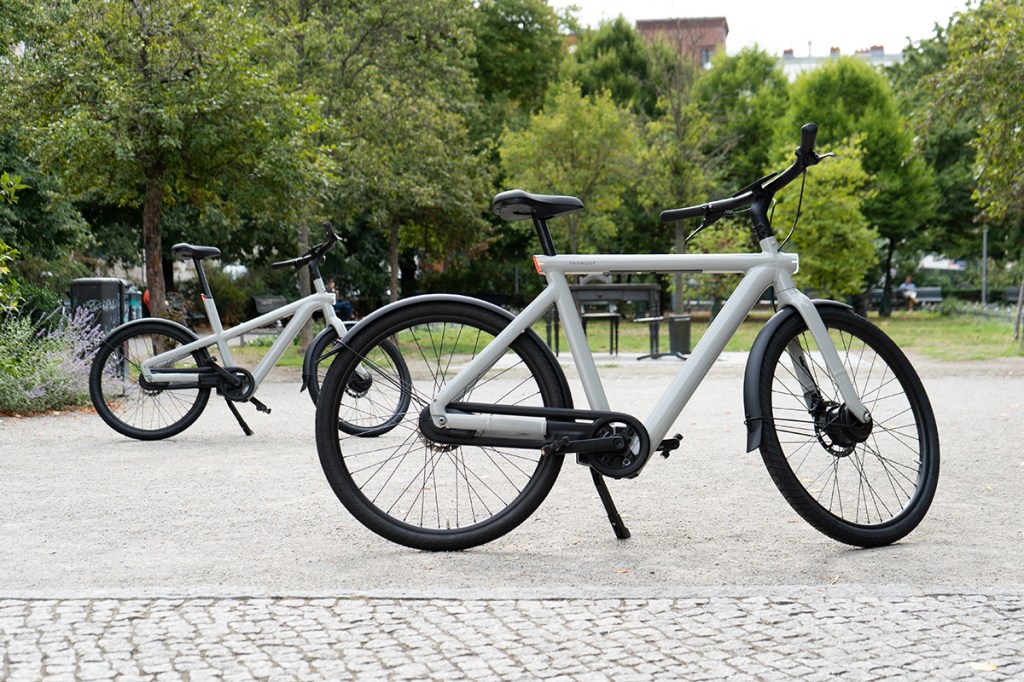 Die beiden City-E-Bikes VanMoof S5 (vorn im Bild) und A5 (Hintergrund) stehen vor einer Parklandschaft.