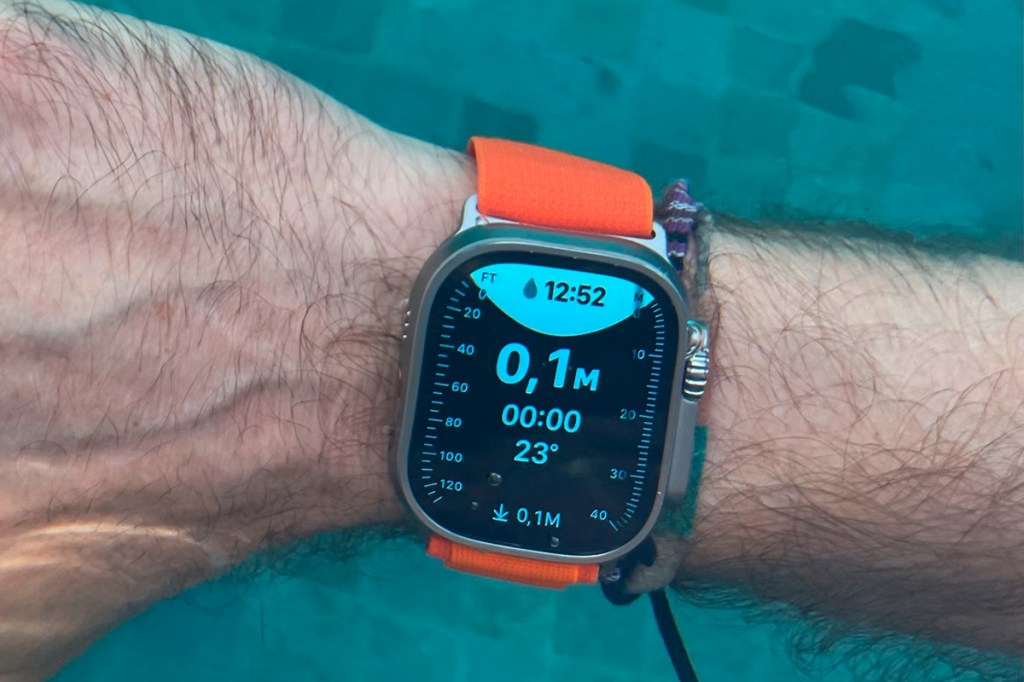 Männerarm mit orangener Apple Watch Ultra und blau leuchtendem Display