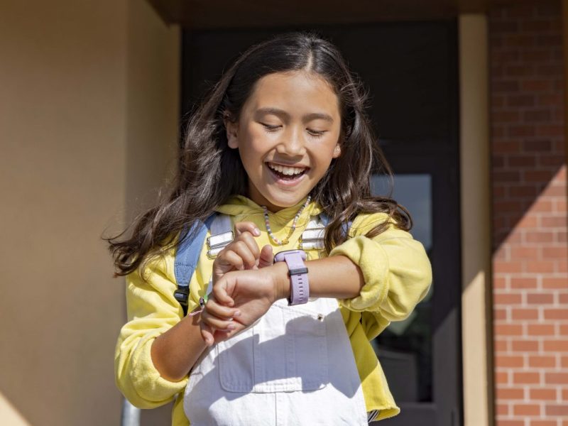 Ein lachendes Mädchen blickt auf ihre Garmin Smartwatch.
