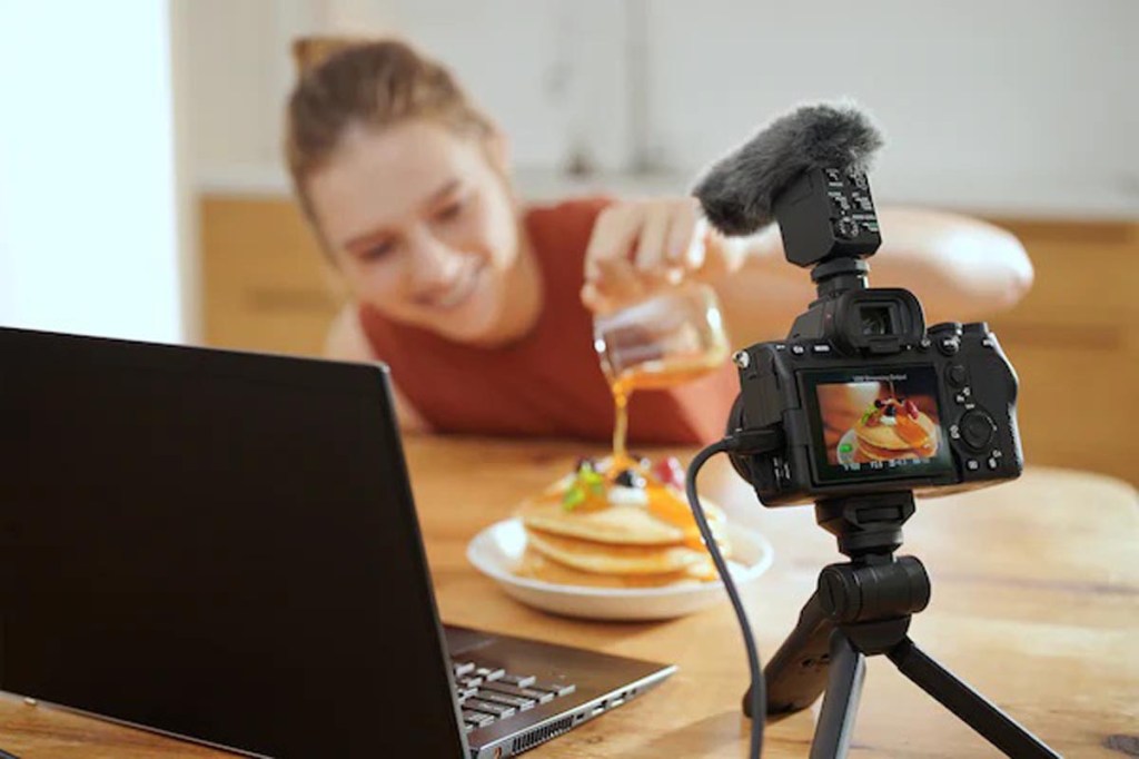 Eine Frau nutzt die Kamera für Foodvideos. Dabei steht die Alpha auf einem Tisch und ist an einen Computer angeschlossen. 