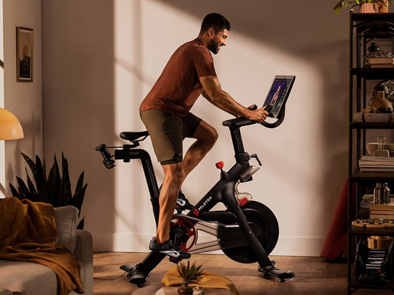 Ein Mann fährt ein Peloton Bike in seiner Wohnung.