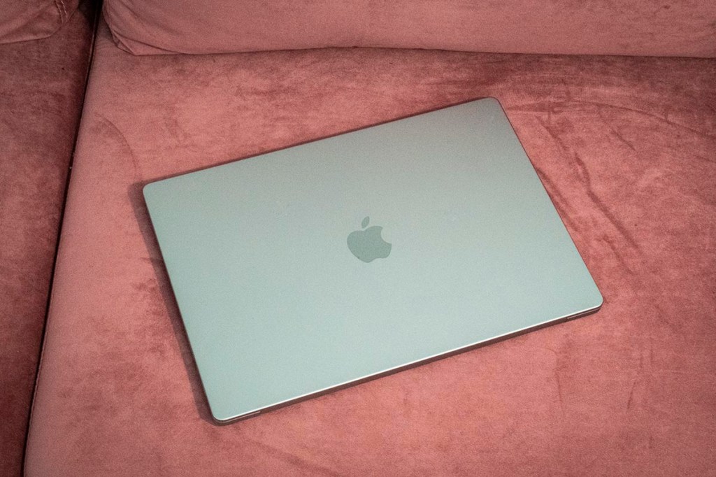 Das Apple MacBook Pro liegt auf einem roten Sofa.