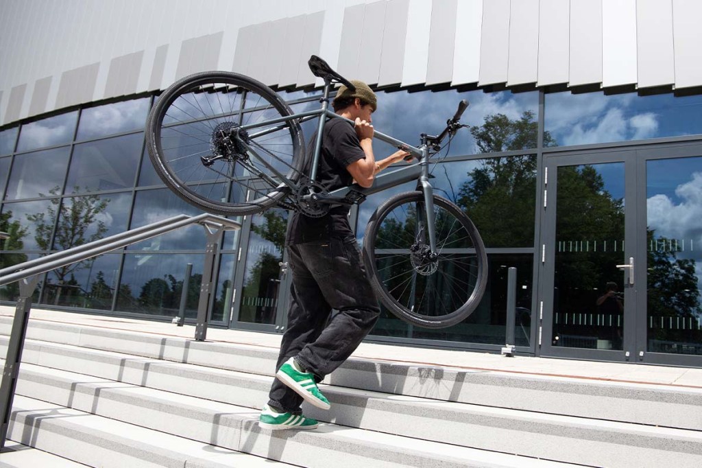 Mann trägt E-bike Sydney von coboc eine Treppe hoch