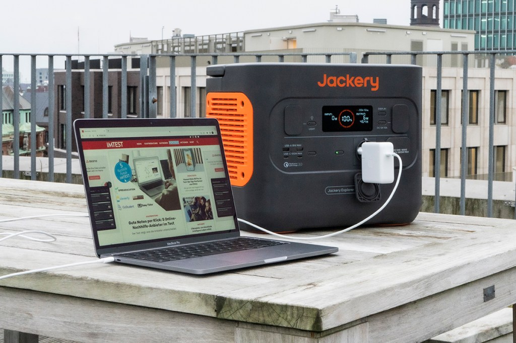 Jackery Explorer 1500 Pro Power Station auf grauem Holztisch neben aufgeklapptem Laptop angeschlossen