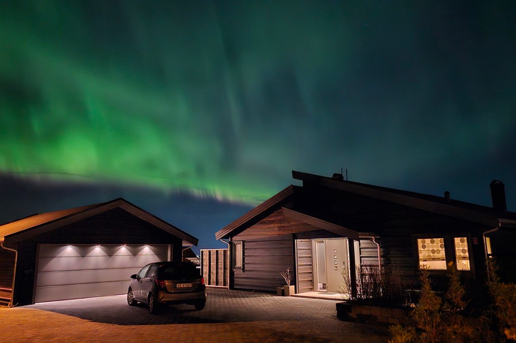 Ein Haus und eine Garage bei Nacht vor Polarlichtern