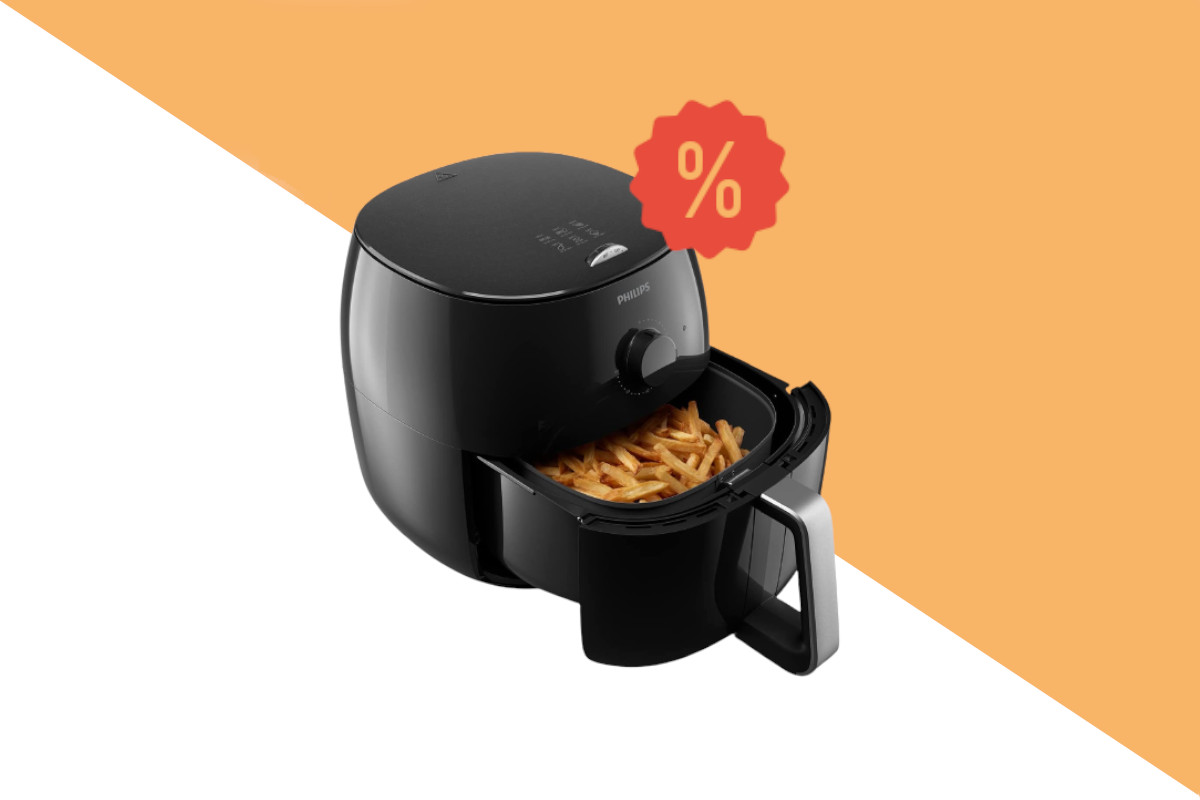 Schwarze Heißluftfritteuse philips Airfryer XXL schräg von vorne mit geöffnetem Korb in dem frittierte Pommes sind auf weiß orangem Hintergrund mit rotem Prozentzeichen rechts oben