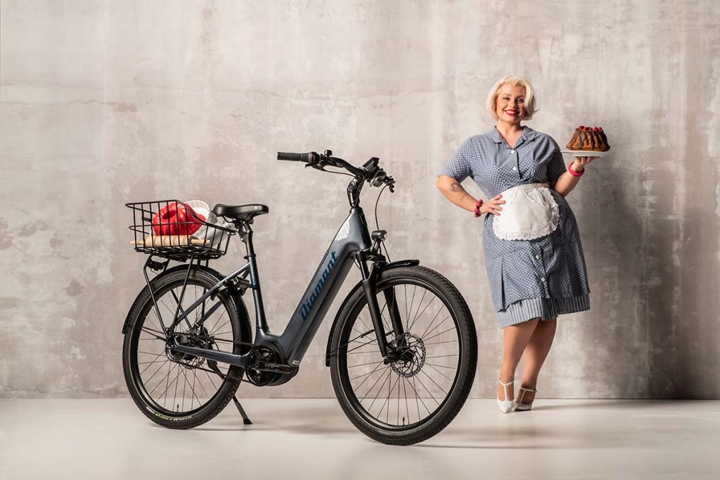 E-Bike Beryll von Diamant, in einer Halle stehend, dahinter steht ein Frau, die einen Kuchen trägt