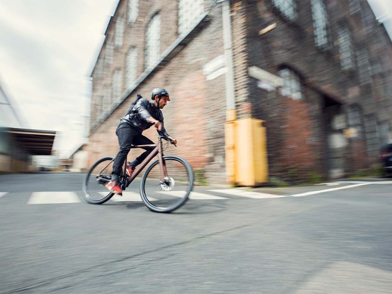 Mann fährt mit E-Bike von Coboc eine leere Straße entlang