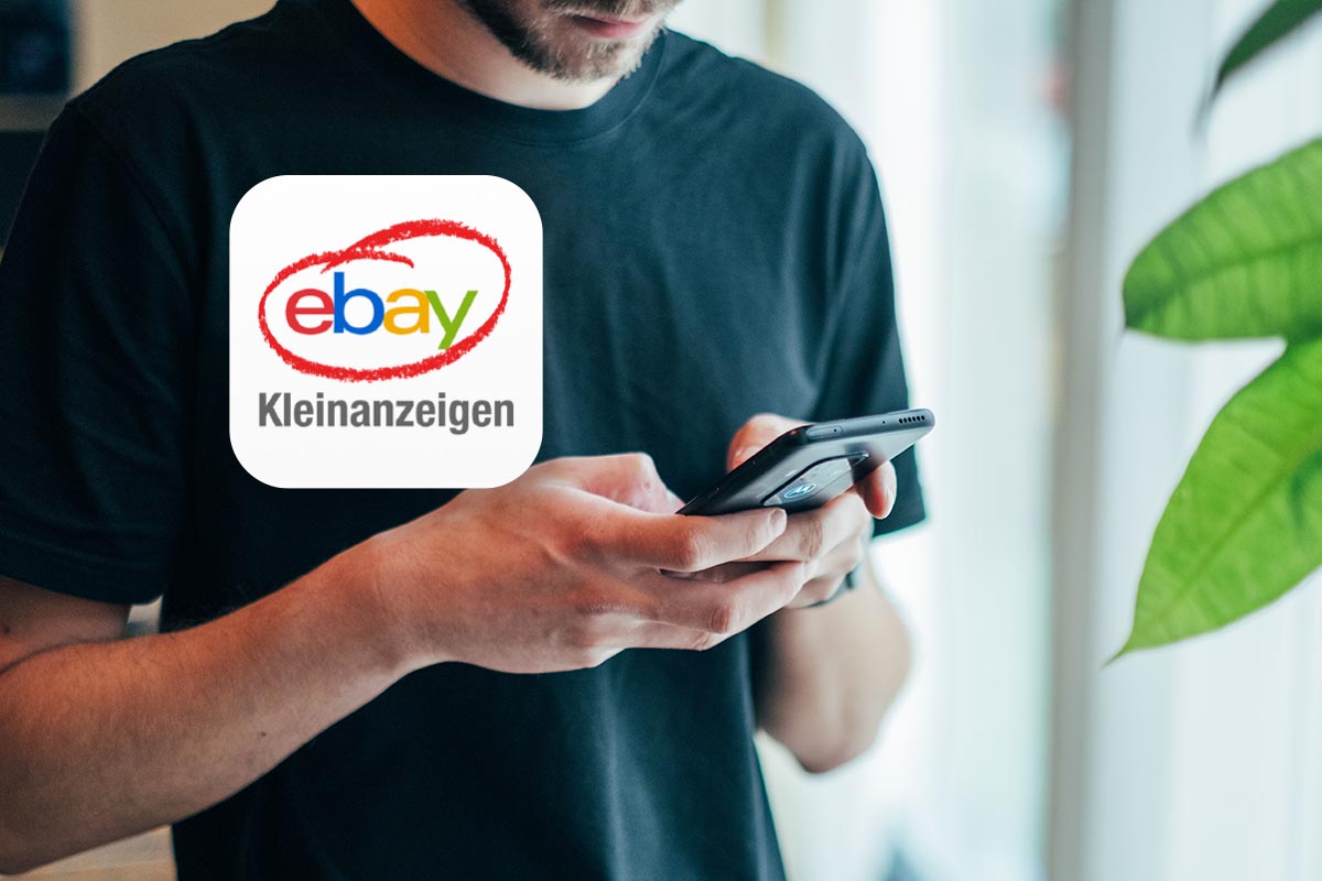 Ein mann hält ein Smartphone in der Hand, davor das Kleinanzeigen-Logo