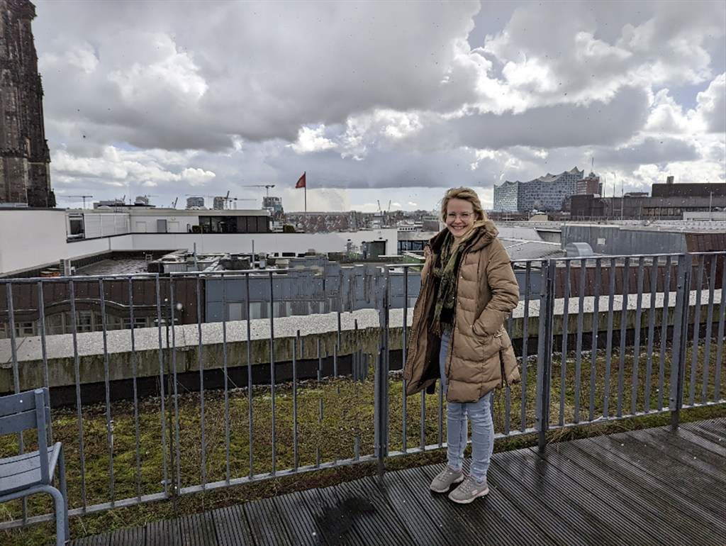 Frau auf Terrasse bei Regen schaut in Kamera