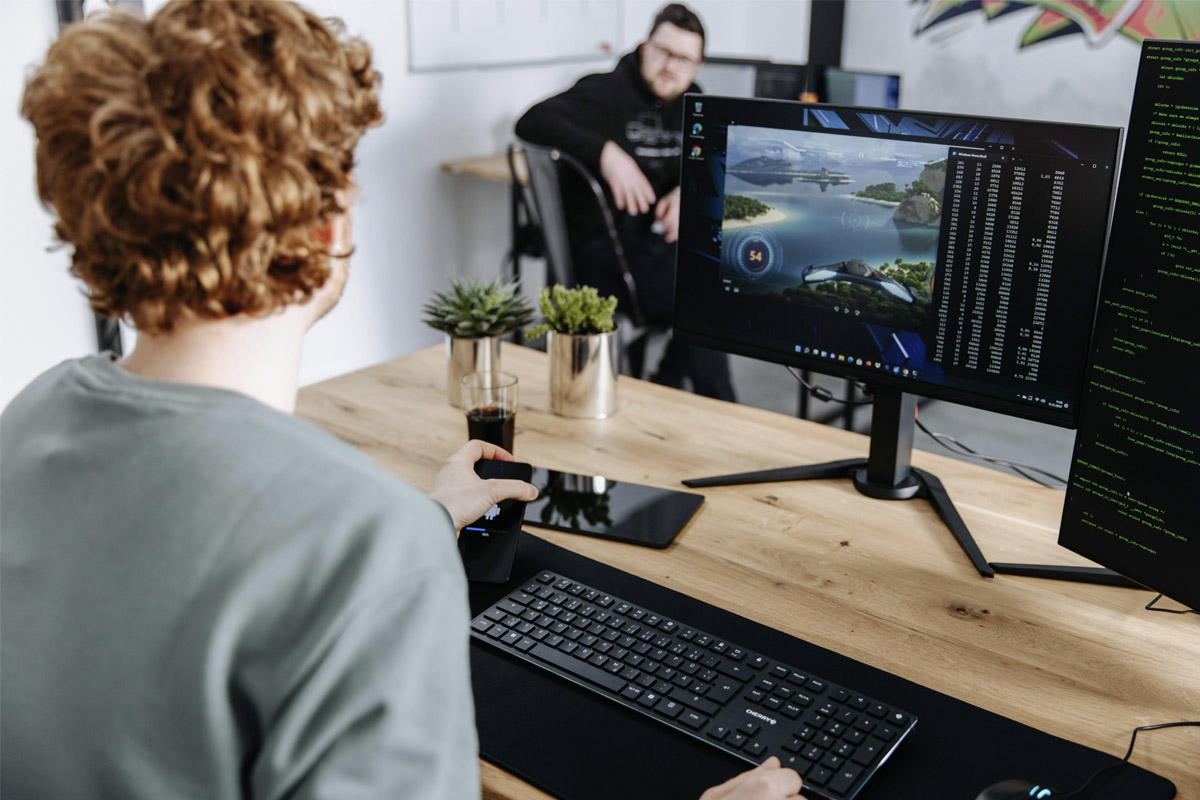 Zwei Männer sitzen an Arbeitsplätzen, einer arbeitet mit einer Cherry Tastatur.