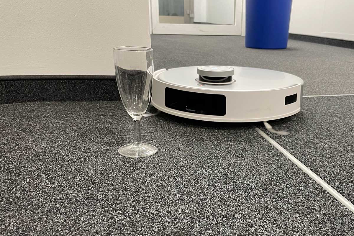 Der Deebot T20 Omni fährt auf ein Glas zu.