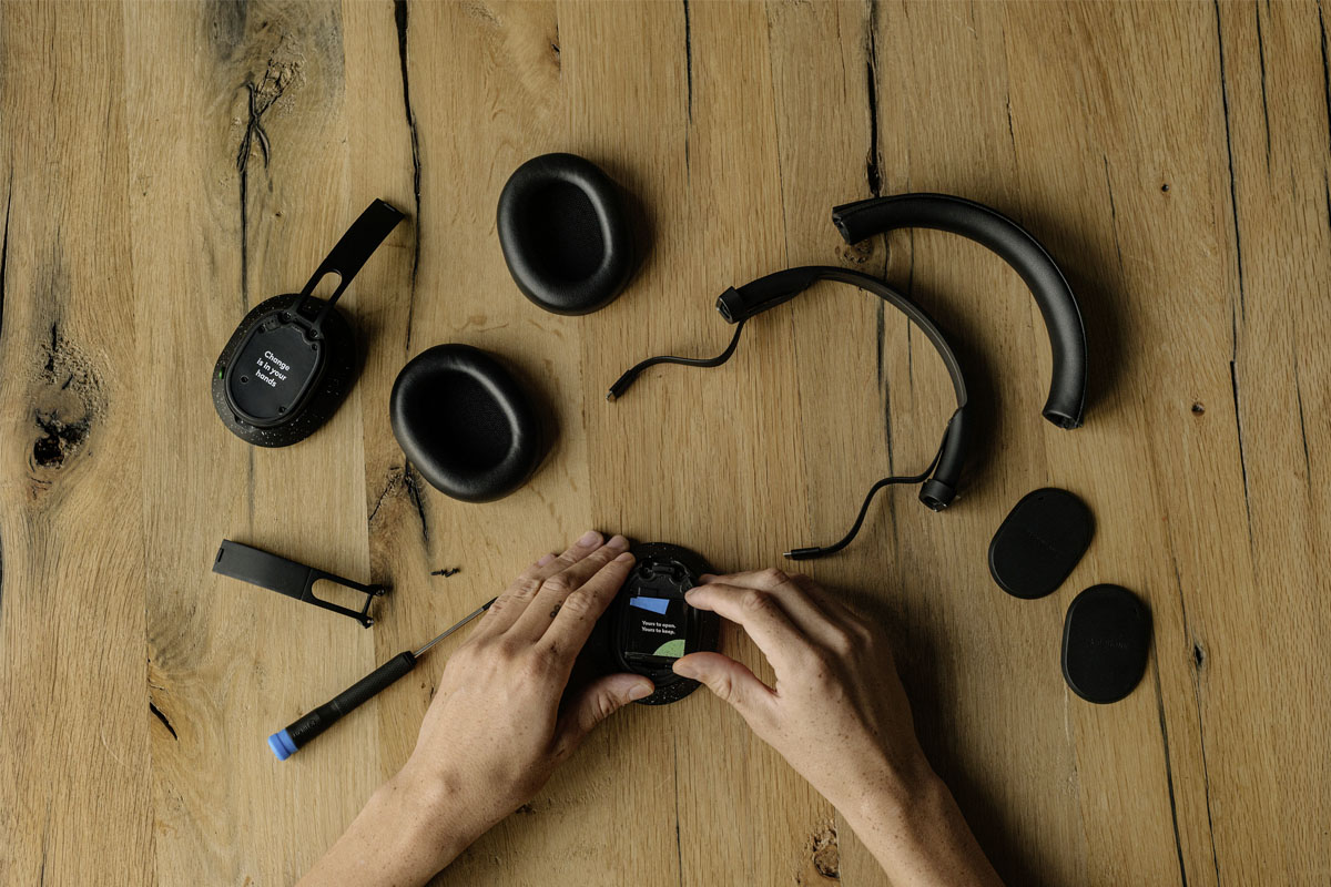 Eine Person repariert die Fairbuds XL Kopfhörer auf einem Holztisch.