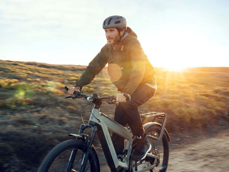 Mann fährt bei Sonnenaufgang mit dem E-Bike durch die Natur