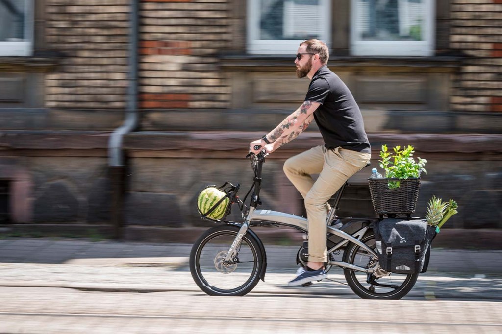 Man fährt mit seinem Falt-E-Bike samt Einkäufen durch die Stadt
