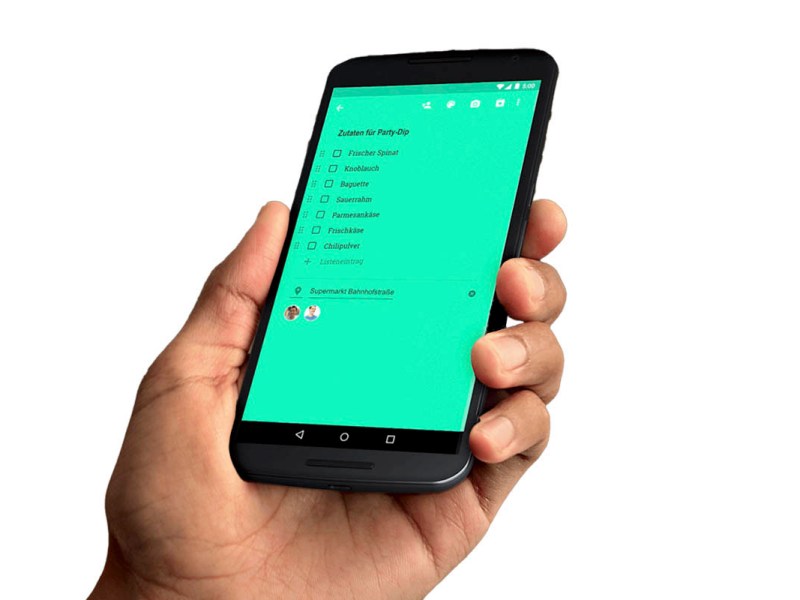Hand hält ein Handy, auf dem eine Liste in Google Notizen mit grünem Hintergrund zu sehen ist