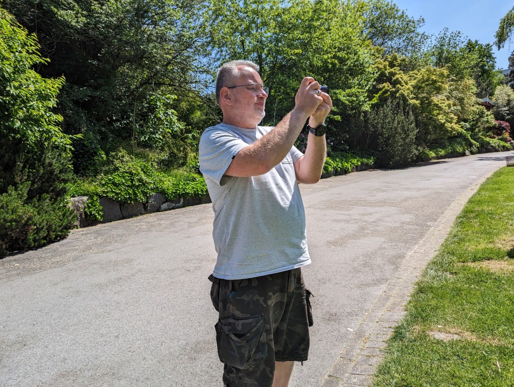 Markus Mizgalski fotografiert mit der Kamera in einer Grünanlage