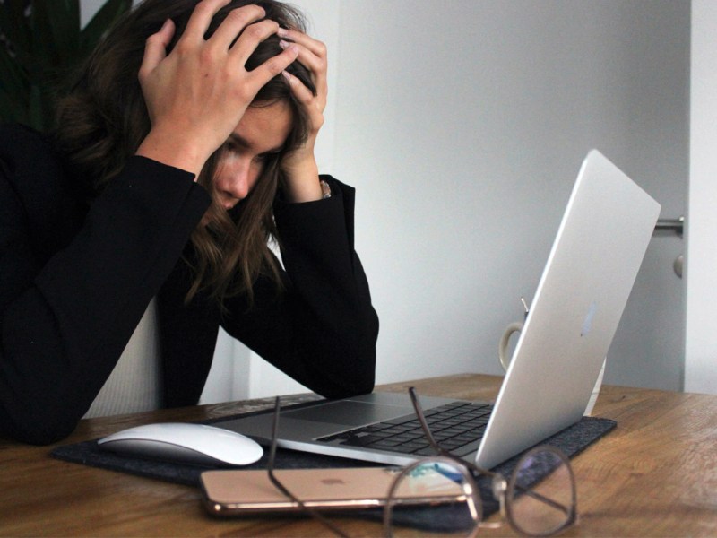 Eine Frau ist verzweifelt und sitzt vor dem Laptop.