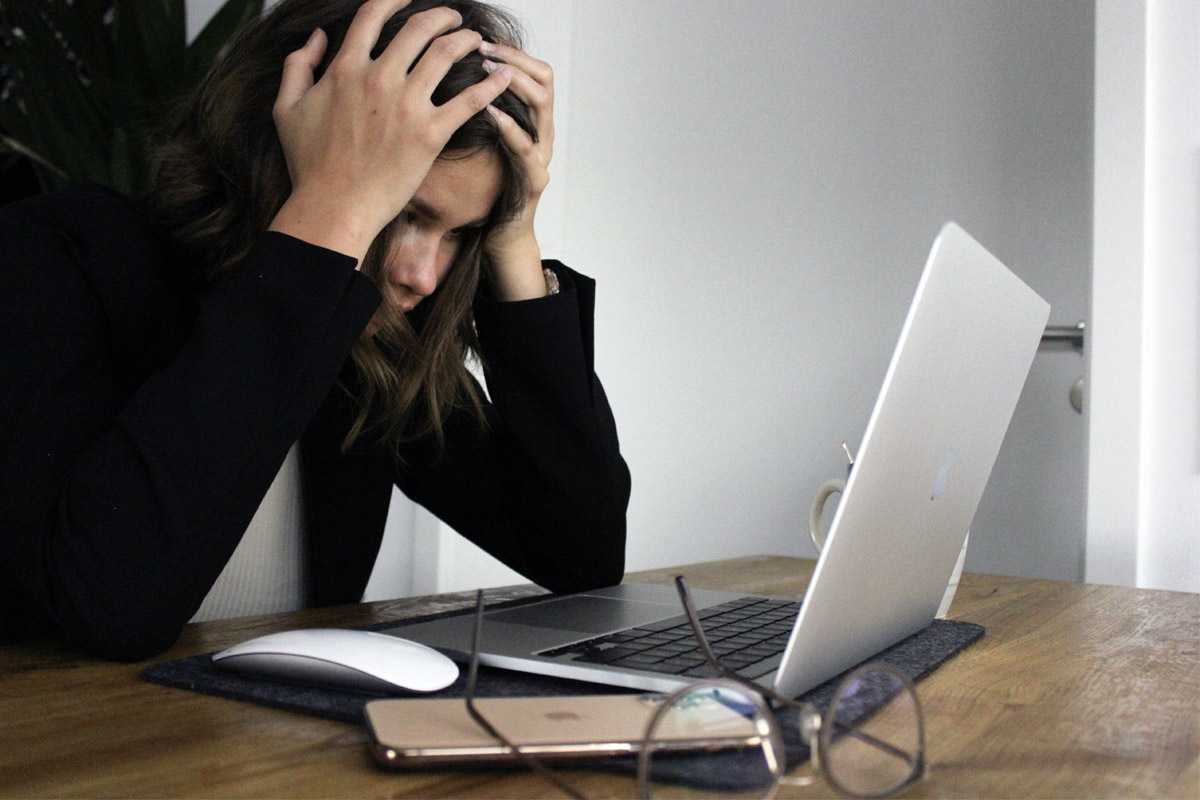 Eine Frau ist verzweifelt und sitzt vor dem Laptop.