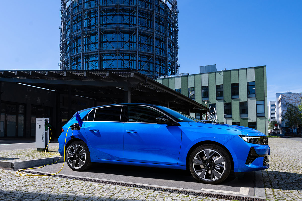 E-Auto Opel Astra Electric steht in städtischer Kulisse vor einem Hochhaus.