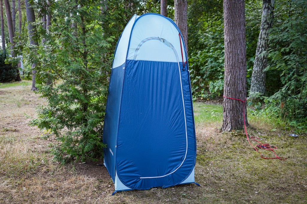 blaues Duschzelt im Wald stehend, Tür geschlossen