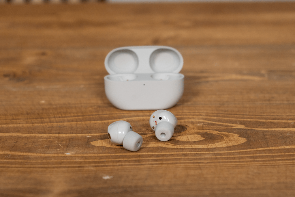 Die grauen Sony In-Ear-Kopfhörer vor ihrem Ladecase auf einem Holztisch.