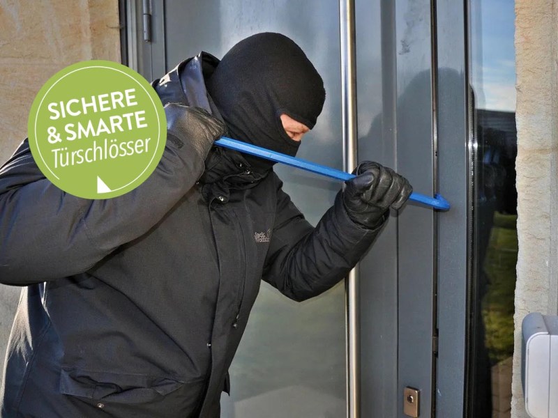 Einbrecher mit Maske an einer Haustür.