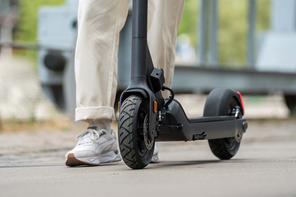 Nahaufnahme Trittbrett von E-Scooter von vorne, daneben sieht man Füße