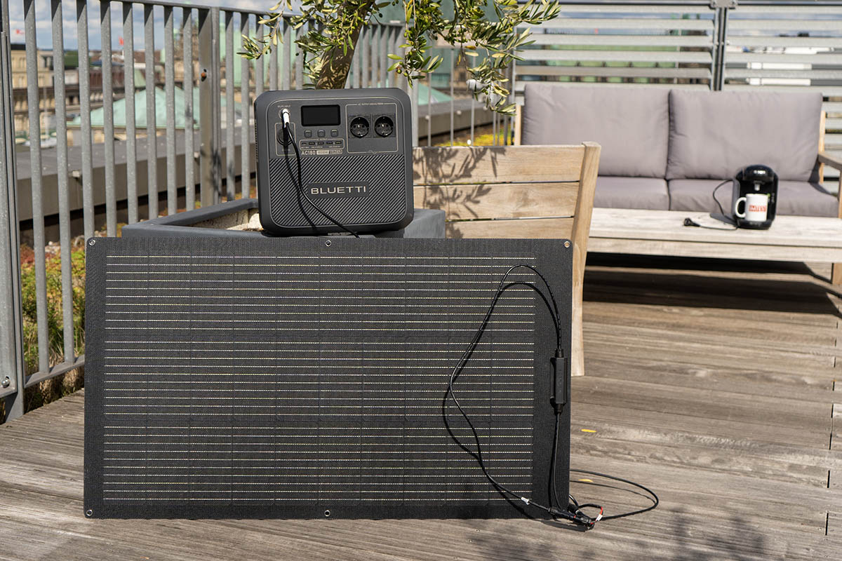 Die Bluetti AC180 Powerstation mit Solarpanel auf einer Dachterrasse in der Sonne.