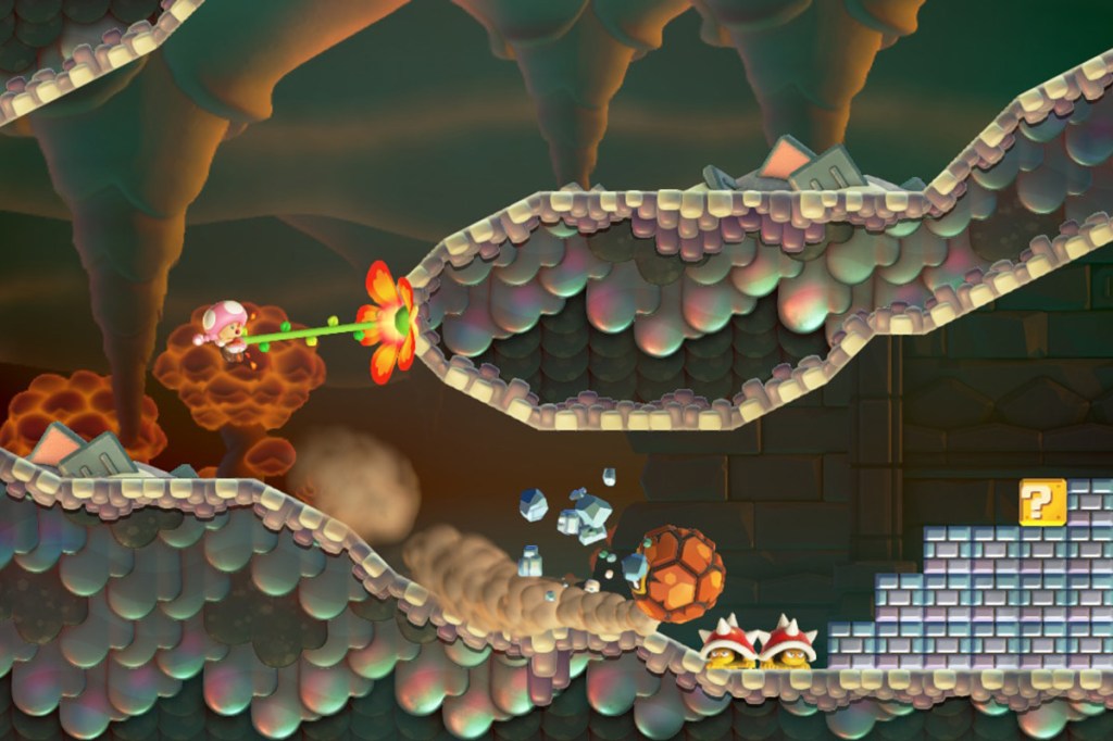 Screenshot aus dem Spiel Super Mario Bros. Wonder. Man sieht die Figur Toadette, die sich mit einer Art Liane an eine Felswand heranzieht.