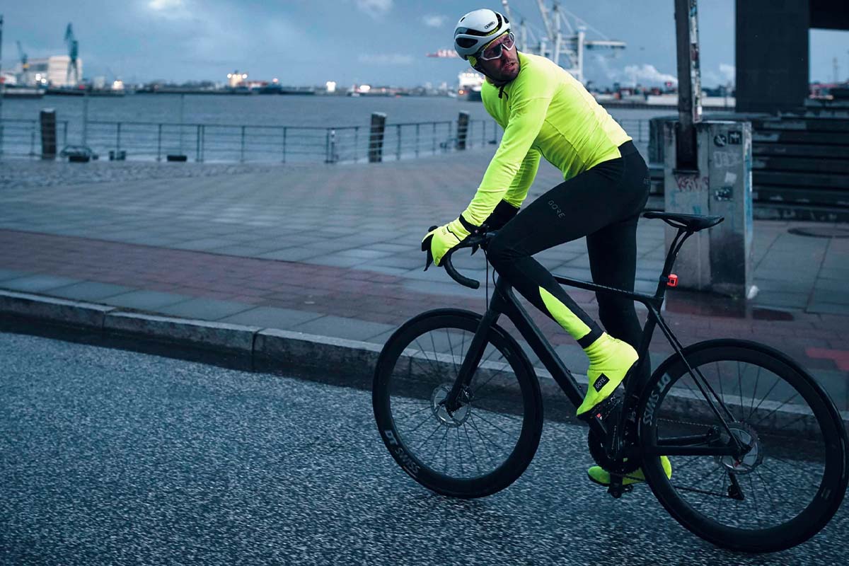 Gravelbikefahrer in der Dämmerung, trägt grelle Kleidung und Überschuhe