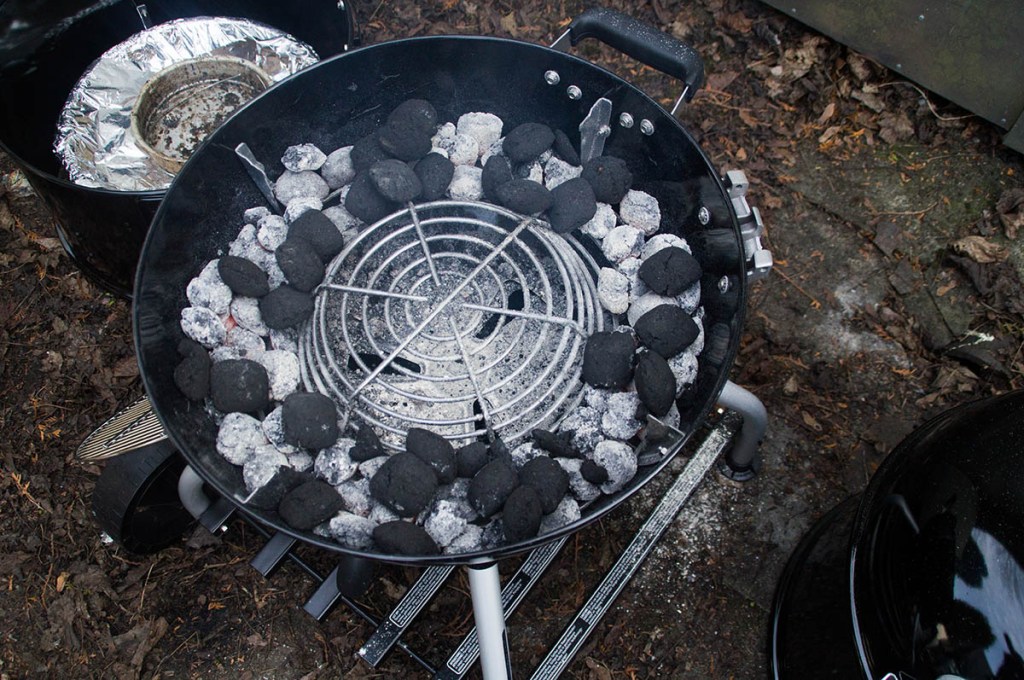 Holzkohle-Briketts im Unterteil eines Wassersmokers beim Wintergrillen