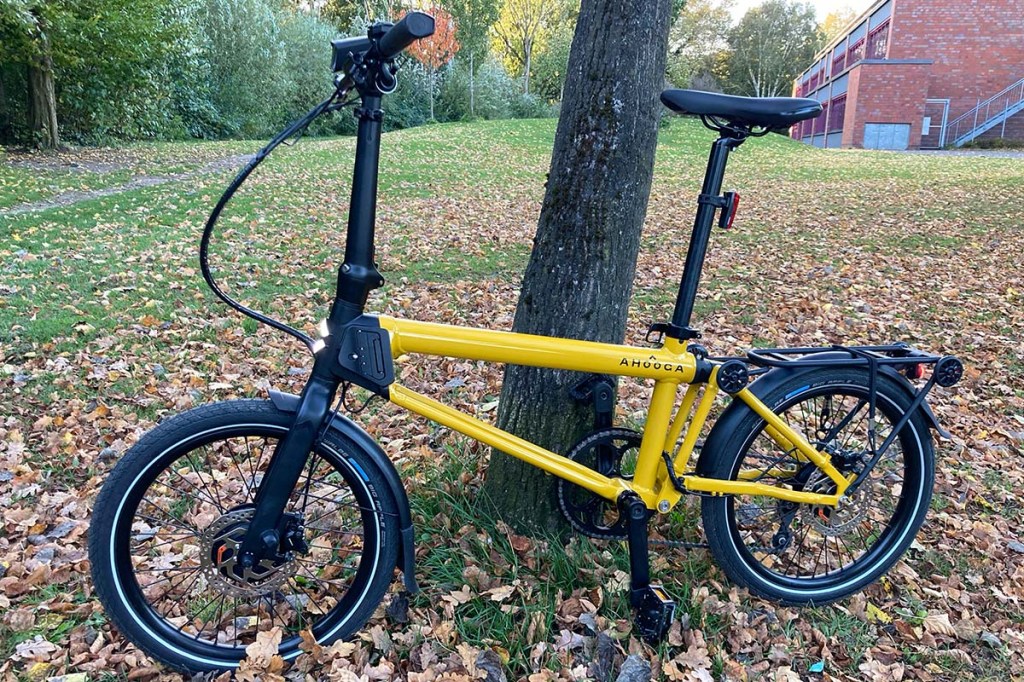 Gelbes Falt-E-Bike an einen Baum gelehnt