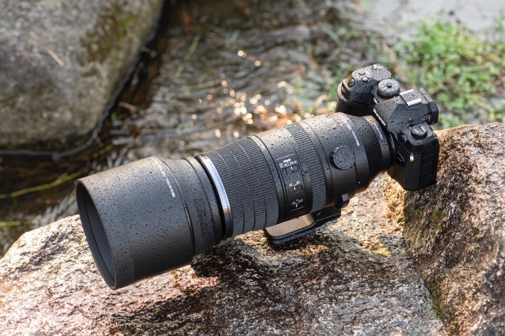 OM-1 Mark II mit Teleobjektiv, von Wassertropfen benetzt.