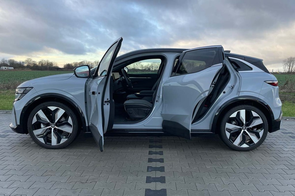 graues Auto von der Seite mit geöffneten Türen, im Hintergrund Felder und wolkiger Himmel