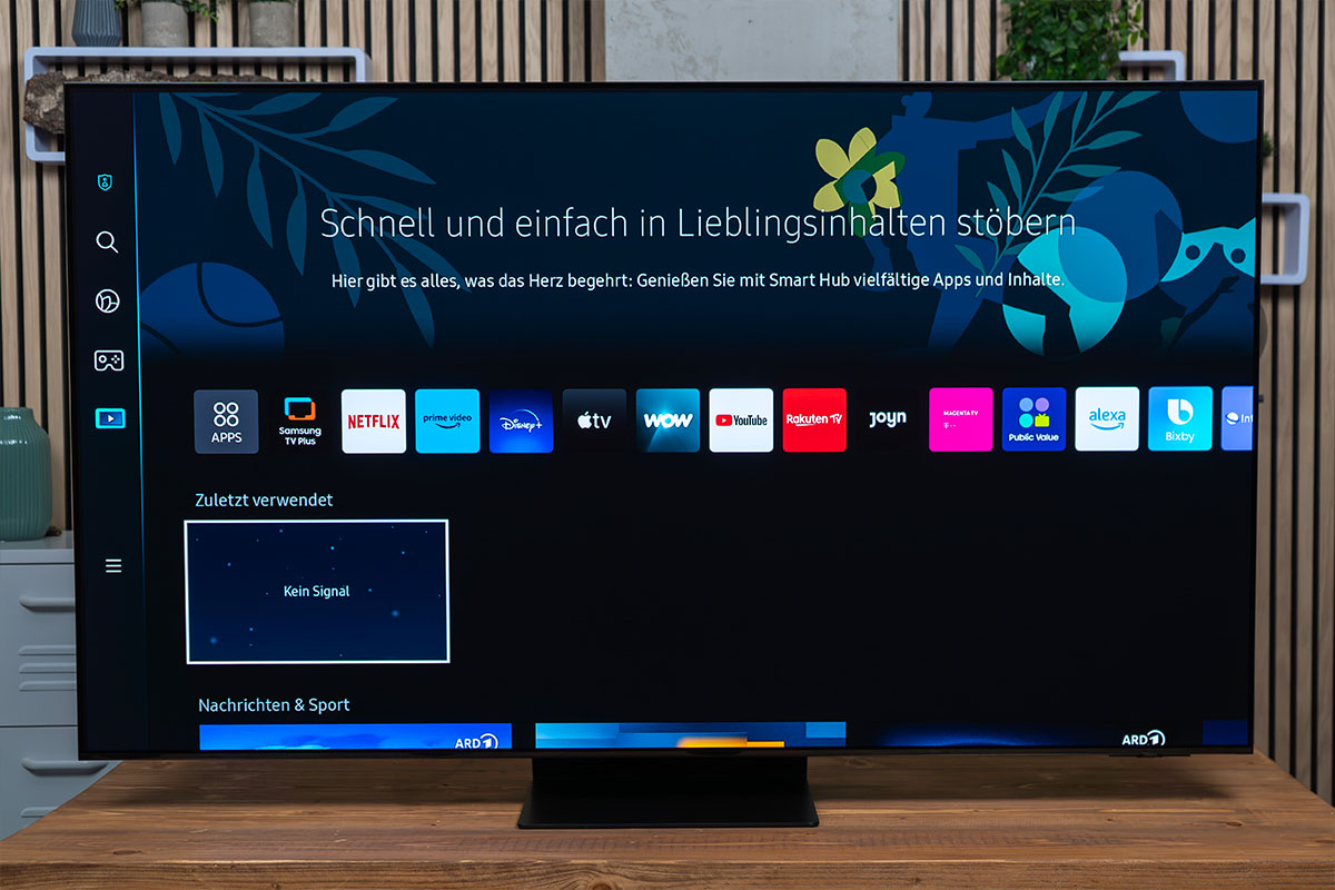 Smart TV von Samsung mit eingeschlatetem Bildschirm stehend und frontal abgelichtet auf einem Holztisch.