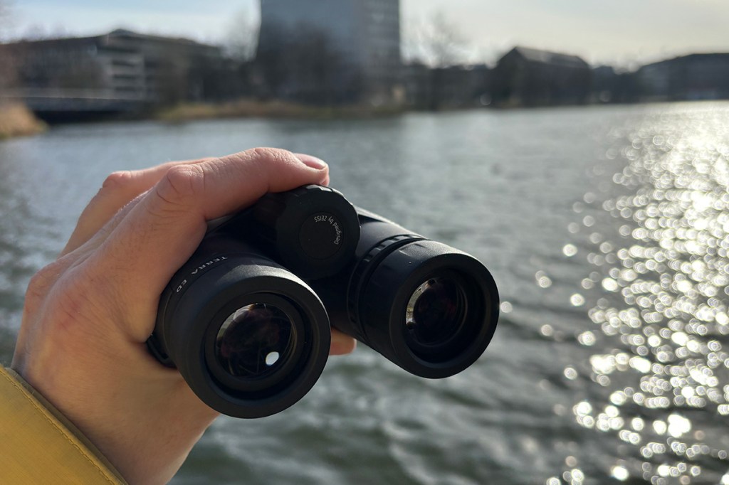 Zeiss Fernglas mit See und Stadt im Hintergrund.