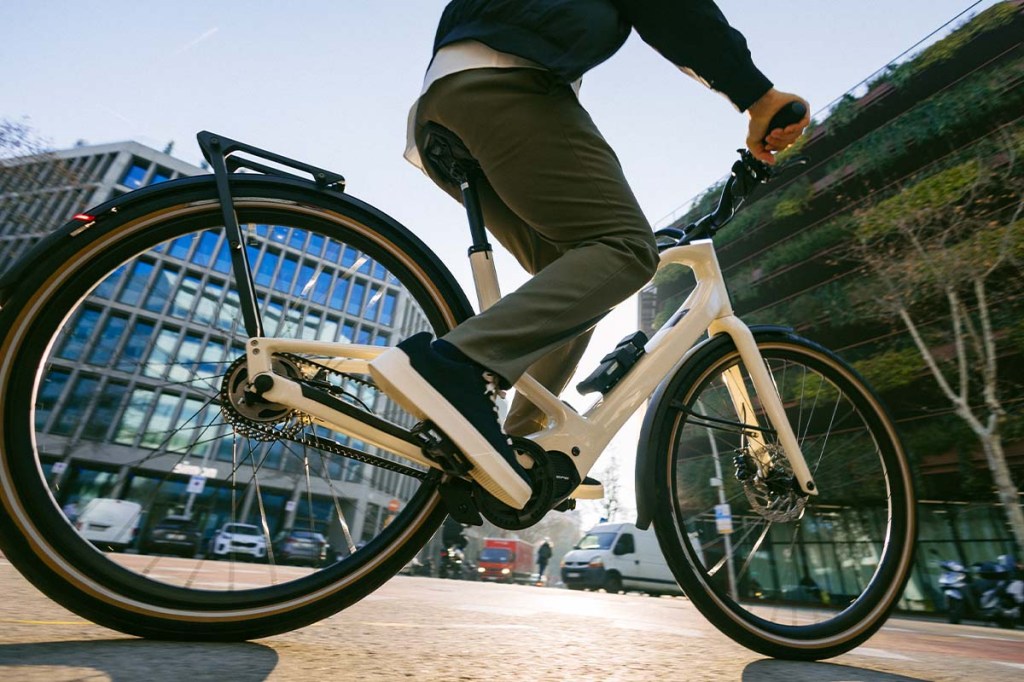 E-Bike mit Fahrer, den man nur beinabwärts sieht, fährt durch eine STadt