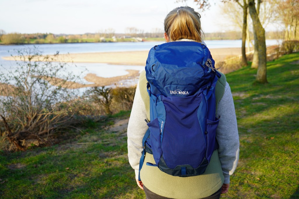 Frau von hinten mit einem blauen Rucksack auf dem Rücken